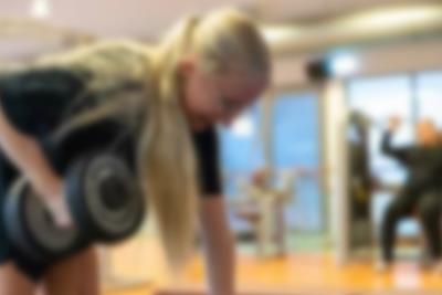 Kvinde tager armbøjninger i fitnesscenter. Få en god træningsoplevelse i ferien I Lalandia.